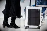 July Carry On Pro being rolled by a passenger in front of a row of seats on an airplane