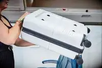person putting the July Carry On Pro into the overhead compartment of an airplane