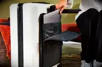 A person places a laptop into the sleeve on a July Carry On Pro SnapSleeve