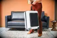 A person uses a luggage scale to weight a July Carry On Pro SnapSleeve