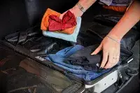 Hands pack clothing into a July Carry On Pro SnapSleeve