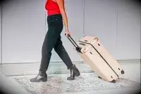 Person rolling the July Checked Plus Large Luggage across a rug