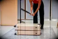 Person hitting the July Checked Plus Large Luggage with a baseball bat