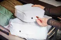 Hands placing packing cubes inside the July Checked Plus Large Luggage