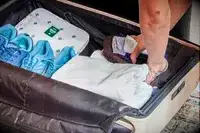 Hands placing clothing in the July Checked Plus Large Luggage