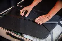 Hands strapping down clothing in the July Checked Plus Large Luggage