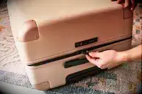 Hand unzipping the July Checked Plus Large Luggage