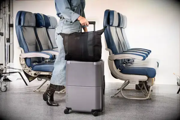 A person rolls the July Carry-on Max down an airplane aisle
