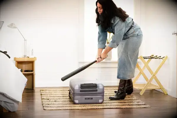 A person hits the July Carry-on Max with a baseball bat