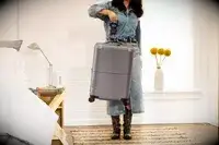 A person weighs the July Carry-on Max