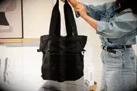 A person holds up the July Carry-on Max tote bag