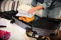 A person places folded clothing into the July Carry-on Max
