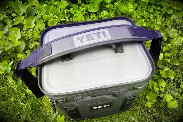 A Yeti Hopper Flip 12 Soft Cooler sits outdoors in foliage