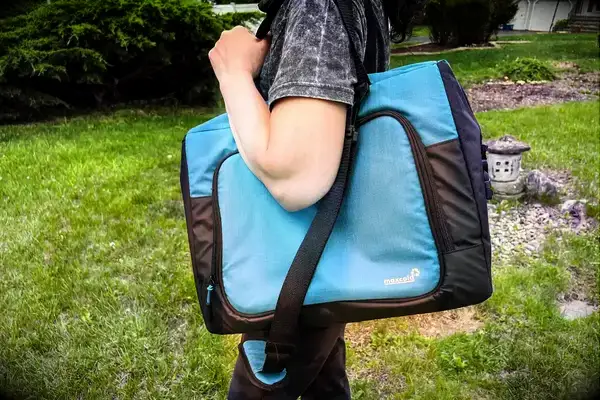 A person carries the Igloo Latitude Snapdown 36-Can Cooler Bag using the shoulder straps