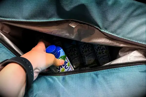 A person places a drink into the Igloo Latitude Snapdown 36-Can Cooler Bag
