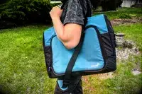 A person carries the Igloo Latitude Snapdown 36-Can Cooler Bag using the shoulder straps