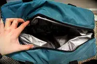 A person holds the Igloo Latitude Snapdown 36-Can Cooler Bag open