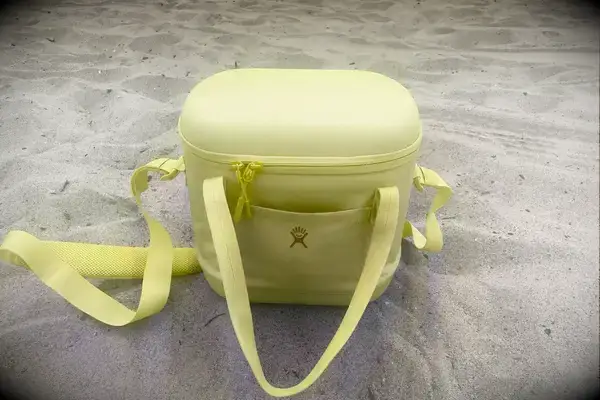 A closed Hydro Flask Carry Out Soft Cooler sits in the sand