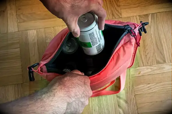 A person places a can into the Monti The Mayfly 14L Cooler