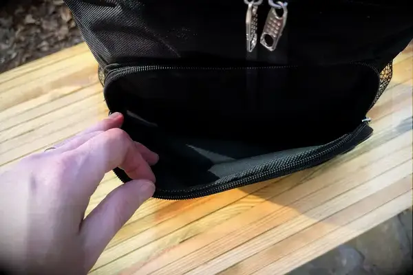 A person opening the front zip pocket of dbest Products Ultra Compact Cooler