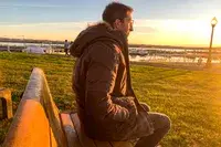 A person sits on a bench while wearing the Kuhl Men