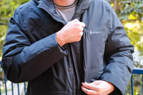 A person unzips the pocket of the Cotopaxi Calidez Men