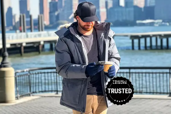 Man using his cellphone and holding a cup of coffee wearing his LL Bean Mens Baster State Parka