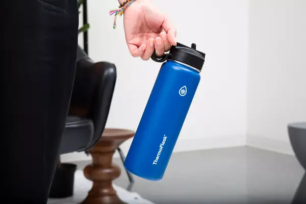 Hand holding a blue Thermoflask Double Wall Vacuum Insulated Stainless Steel Water Bottle