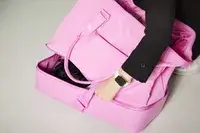 Hand opening the bottom compartment of Béis The Weekender Travel Bag on white floor