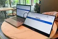 The SideTrak Solo Pro Touch FHD 13.3 next to a laptop sitting on a cafe table