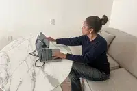 A person sitting at a table working on a laptop and using the The SideTrak Solo Pro Touch FHD 13.3