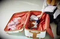 A person adding items into the Delsey Paris Chatelet Air 2.0 26 Inch Trunk