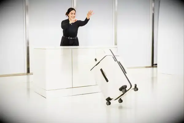 A person pushing the Travelpro x Travel & Lanetrek Large Check-In Trunk Spinner off of a counter