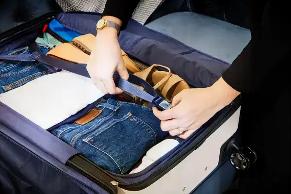 A person buckling items into the Travelpro x Travel & Lanetrek Large Check-In Trunk Spinner