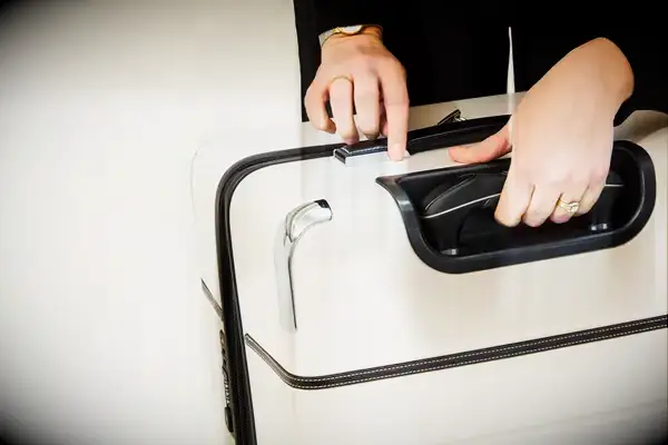 A person locking the Travelpro x Travel & Lanetrek Large Check-In Trunk Spinner
