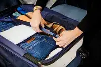 A person buckling items into the Travelpro x Travel & Lanetrek Large Check-In Trunk Spinner