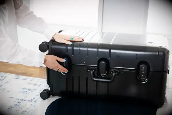 A person secures the lock on the Monos Aluminum Trunk