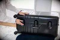 A person secures the lock on the Monos Aluminum Trunk