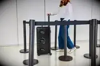 A person wheels the Monos Aluminum Trunk over linoleum