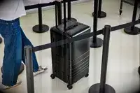 A person wheels the Monos Aluminum Trunk over aluminum