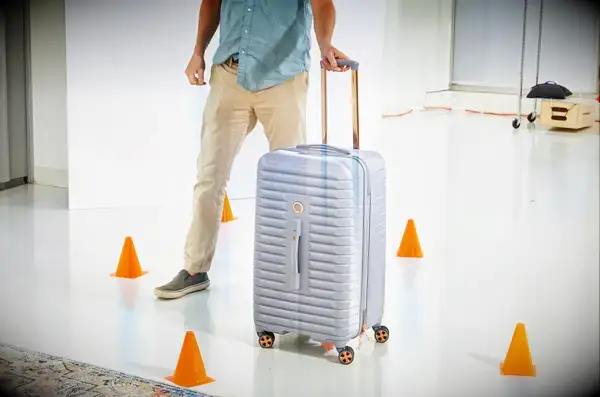 A person rolling the Delsey Paris Cruise 3.0 26 Inch Trunk through cones