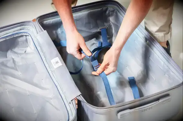 Two hands holding the strap inside of the Delsey Paris Cruise 3.0 26 Inch Trunk