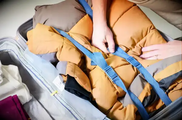 A hand touching the strap inside of a backed Delsey Paris Cruise 3.0 26 Inch Trunk