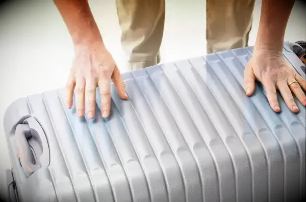 Two hands pushing the Delsey Paris Cruise 3.0 26 Inch Trunk closed