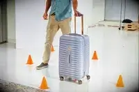 A person rolling the Delsey Paris Cruise 3.0 26 Inch Trunk through cones