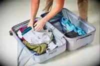 two hands placing items into the Delsey Paris Cruise 3.0 26 Inch Trunk