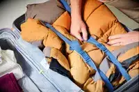 A hand touching the strap inside of a backed Delsey Paris Cruise 3.0 26 Inch Trunk