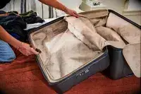 Two hands holding an empty Briggs & Riley Extra Large Trunk Spinner