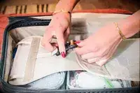 Two hands holding the strap on the Briggs & Riley Extra Large Trunk Spinner