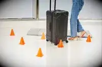 A person wheeling the Briggs & Riley Extra Large Trunk Spinner through orange cones